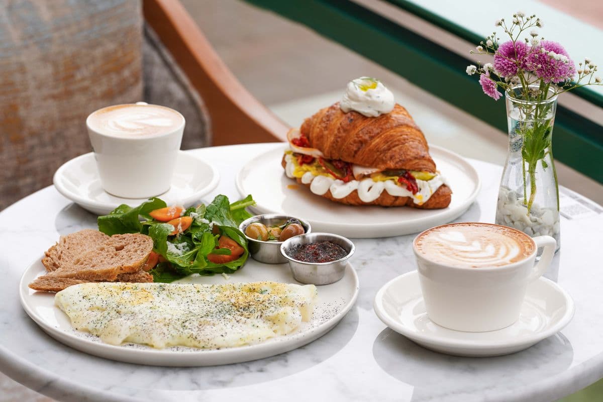 Brunch on a marble table: coffee, croissant sandwich and an omelette