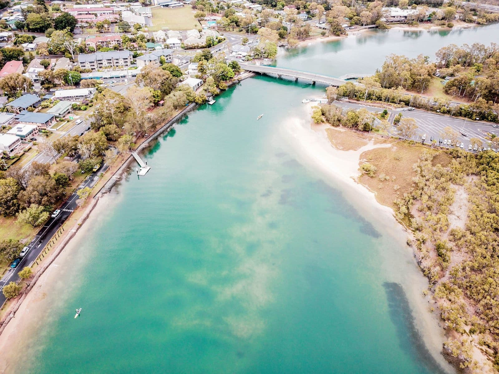 Aerial view of clear green water winding past riverside homes