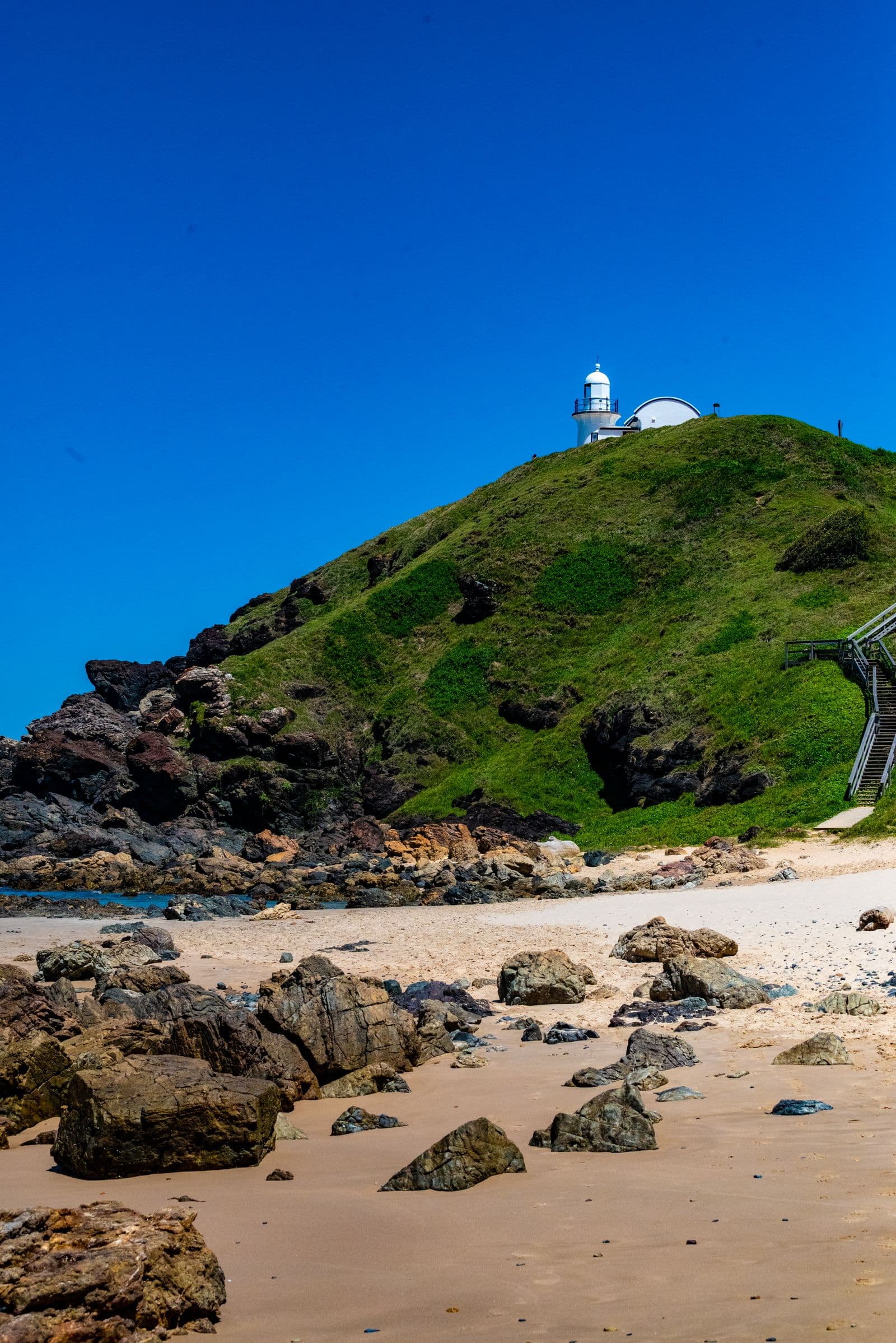 Tacking Point Lighthouse on its green headland above Lighthouse Beach